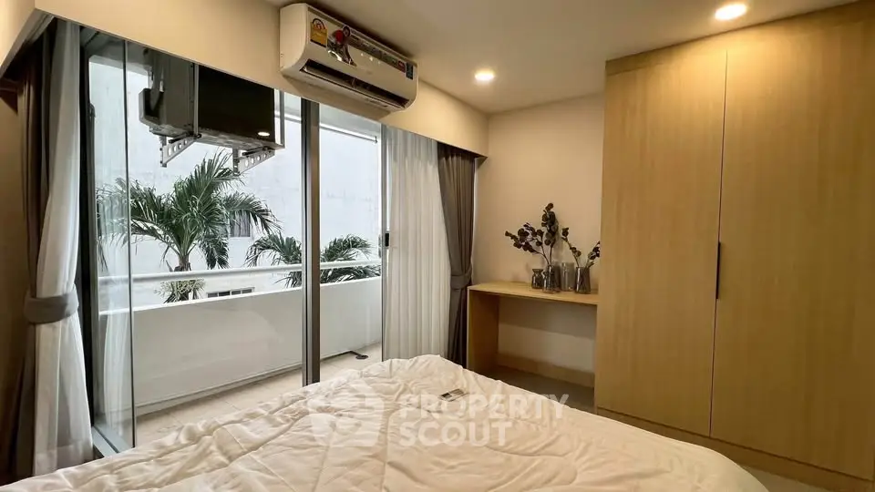 Cozy bedroom with balcony access, featuring modern wardrobe and air conditioning.