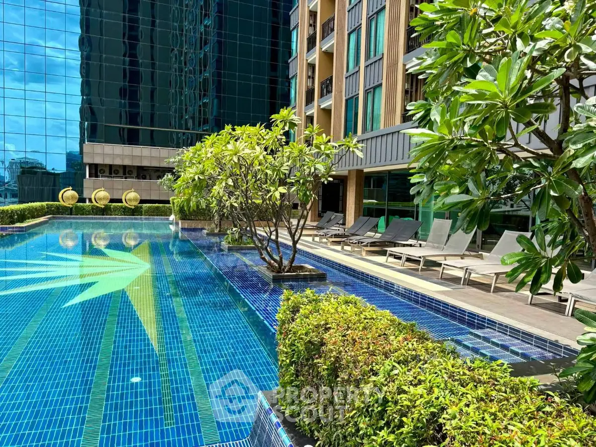 Luxurious outdoor pool area with modern design and lush greenery in a high-rise building complex.
