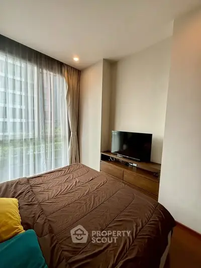 Cozy bedroom with modern decor and large window offering natural light