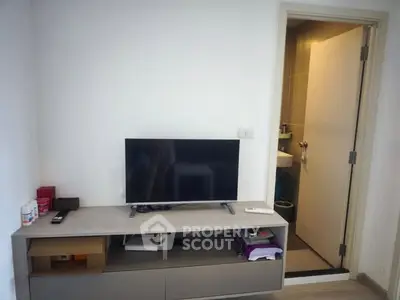 Modern living room with TV and open bathroom door, compact and functional space.