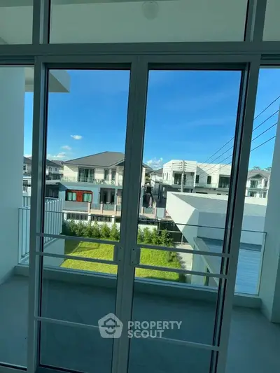 Modern balcony view with clear blue sky and residential neighborhood.