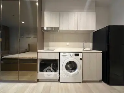 Modern compact kitchen with washing machine and sleek appliances in stylish apartment.