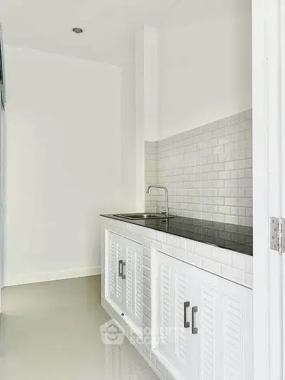 Sleek modern kitchen with white cabinetry and subway tile backsplash, perfect for contemporary living.