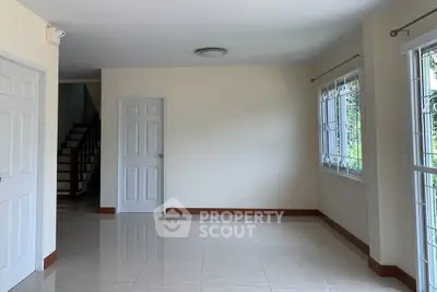 Spacious empty room with tiled flooring and large windows, perfect for customization.