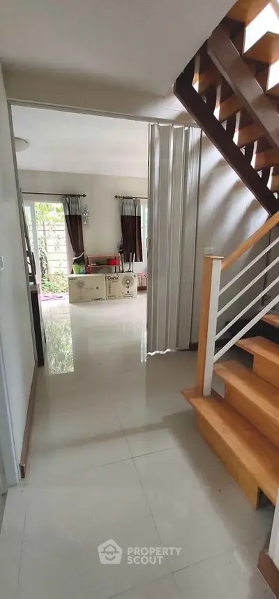 Spacious modern living area with wooden staircase and natural light, perfect for family gatherings.