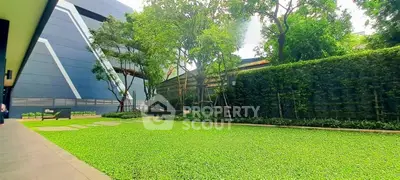 Lush green garden area with modern building backdrop, perfect for relaxation and outdoor activities.