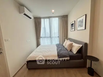 Modern bedroom with large window and stylish decor in a high-rise apartment.