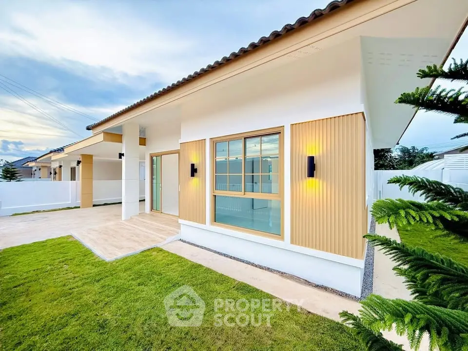 Modern single-story home with manicured lawn and stylish exterior lighting.