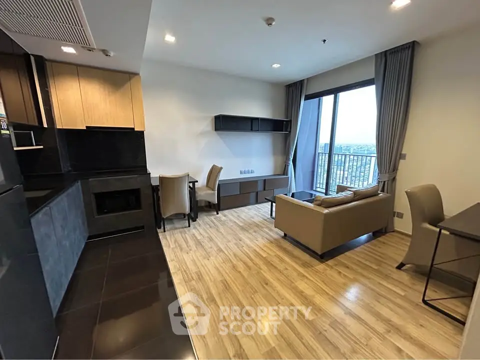 Modern open-layout living room with kitchen, featuring sleek furniture and a balcony view.