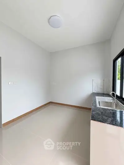 Modern minimalist kitchen with sleek countertops and large window for natural light.