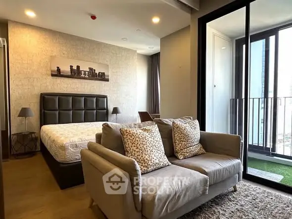 Modern bedroom with cozy seating and balcony view in luxury apartment.