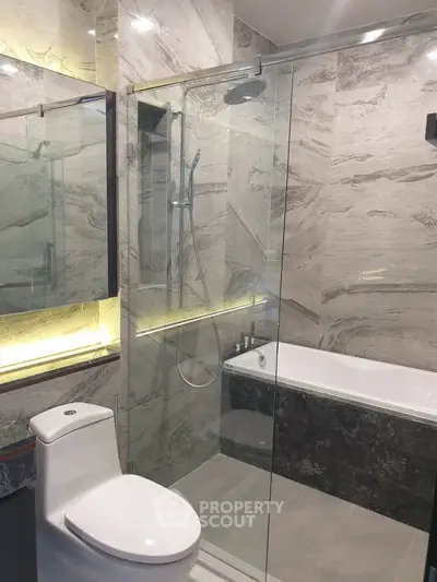 Luxurious modern bathroom with elegant marble finish and glass shower enclosure.