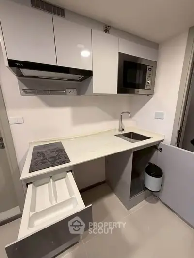 Modern compact kitchen with sleek cabinetry and built-in appliances in a stylish apartment.