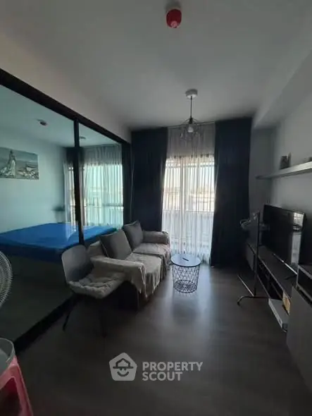 Modern living room with glass partition, cozy seating, and natural light.