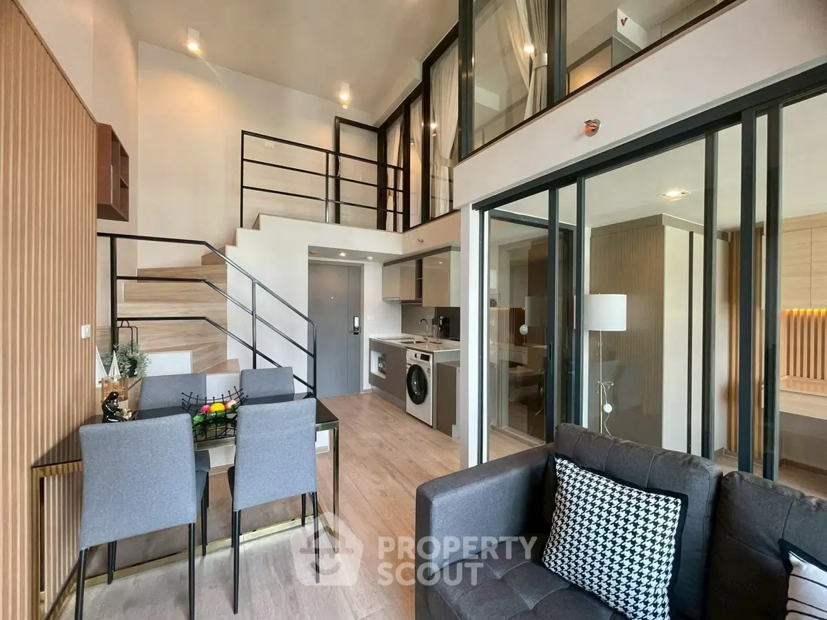 Modern duplex apartment with stylish interior, featuring open living area, dining space, and loft bedroom.