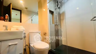Modern bathroom with glass shower and sleek fixtures in contemporary apartment.