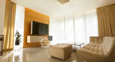 Luxurious modern living room with elegant furniture and large TV, bathed in natural light.