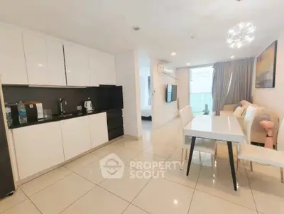 Modern open-plan living room and kitchen with sleek white cabinets and elegant dining area.