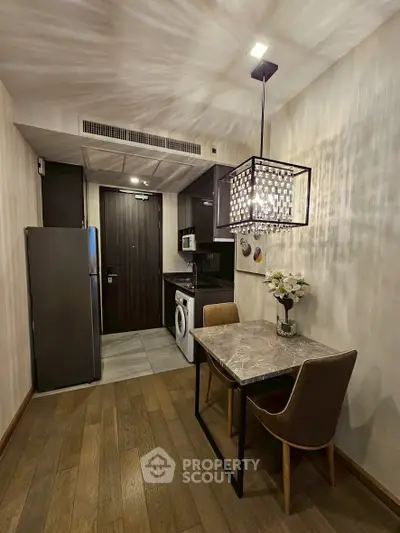 Modern kitchen with dining area, featuring sleek appliances and elegant lighting in a compact space.