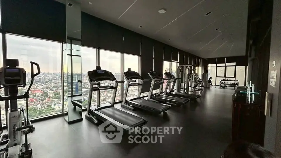 Modern gym with panoramic city views and state-of-the-art equipment in luxury high-rise building.