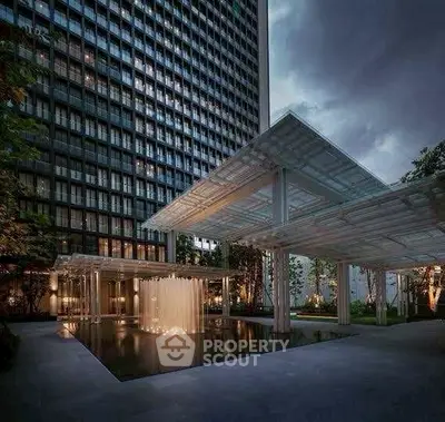 Luxurious modern building exterior with elegant water feature at dusk.