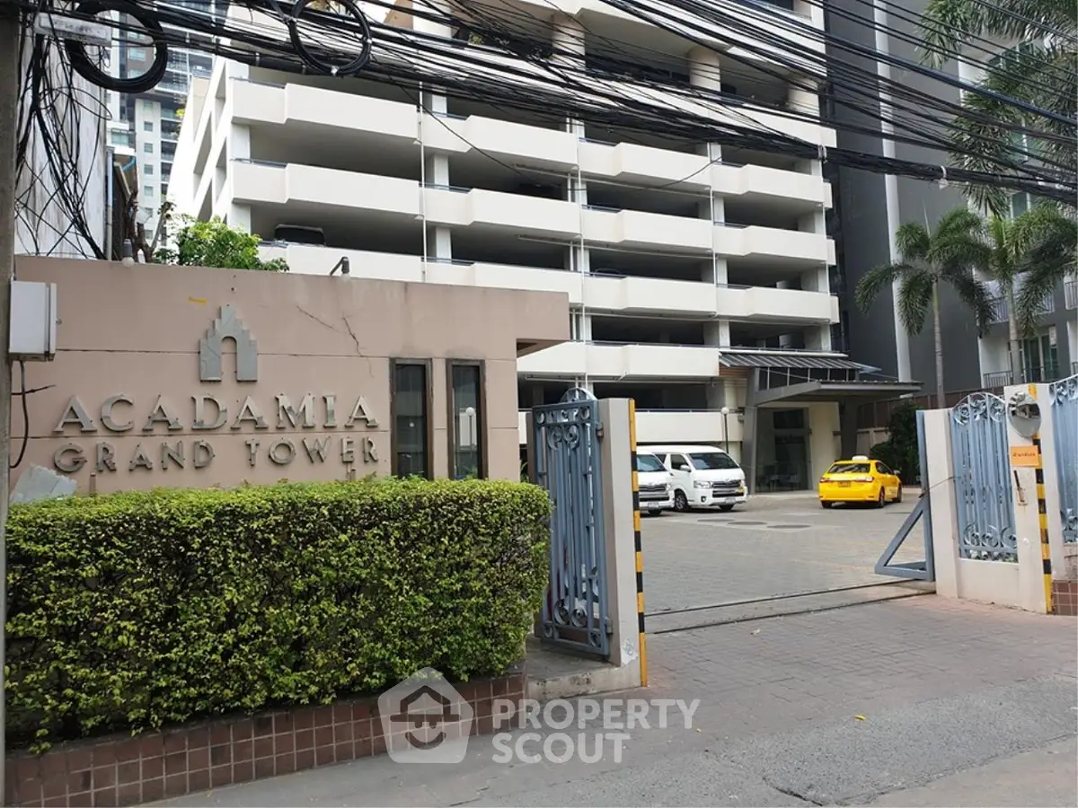 Modern high-rise building entrance with gated access and lush greenery.
