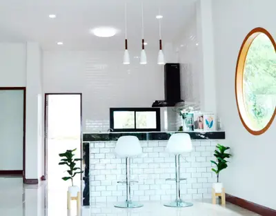 Modern kitchen with sleek bar stools and stylish lighting in a bright, open space.