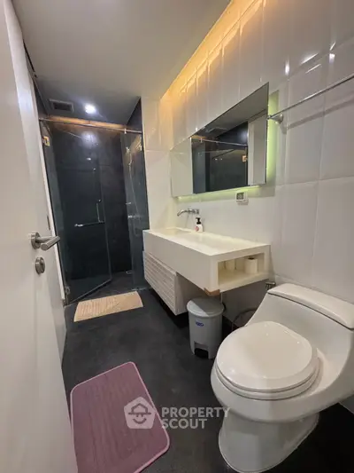 Modern bathroom with sleek design, featuring a glass shower and contemporary fixtures.