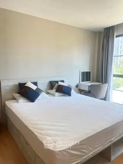 Spacious bedroom with modern decor and large window offering natural light.