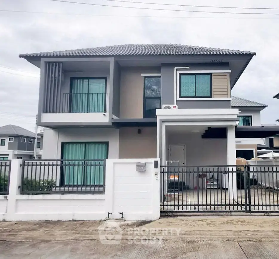 Modern two-story house with gated entrance and contemporary design.