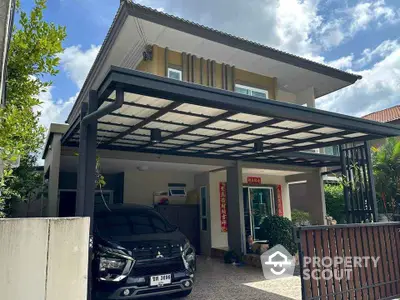 Modern two-story house with carport and lush greenery under a bright blue sky.