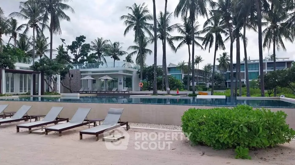 Luxurious beachfront property with pool and palm trees, perfect for a tropical getaway.