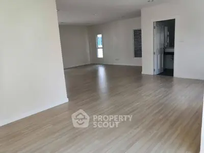 Spacious open-plan living area with wooden flooring and ample natural light