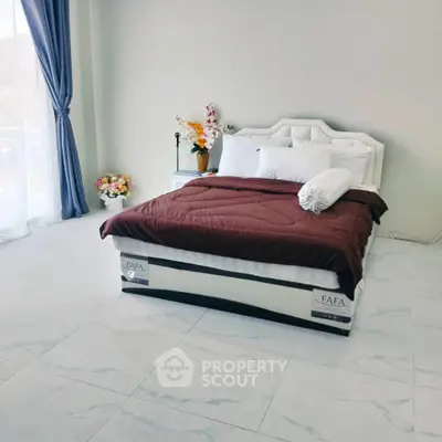 Spacious bedroom with elegant decor and large windows for natural light.