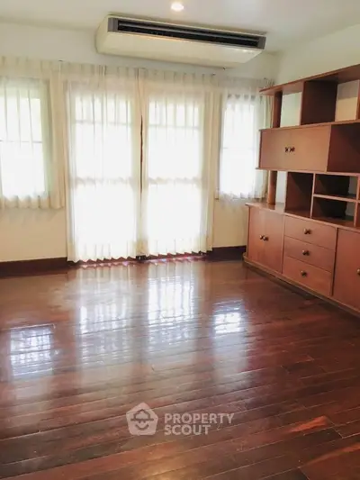 Spacious living room with wooden floors and built-in shelving, perfect for modern living.