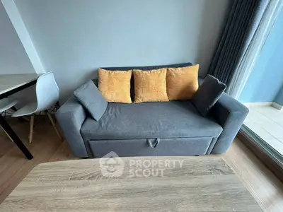Modern living room with cozy gray sofa and vibrant cushions, adjacent to dining area and balcony view.
