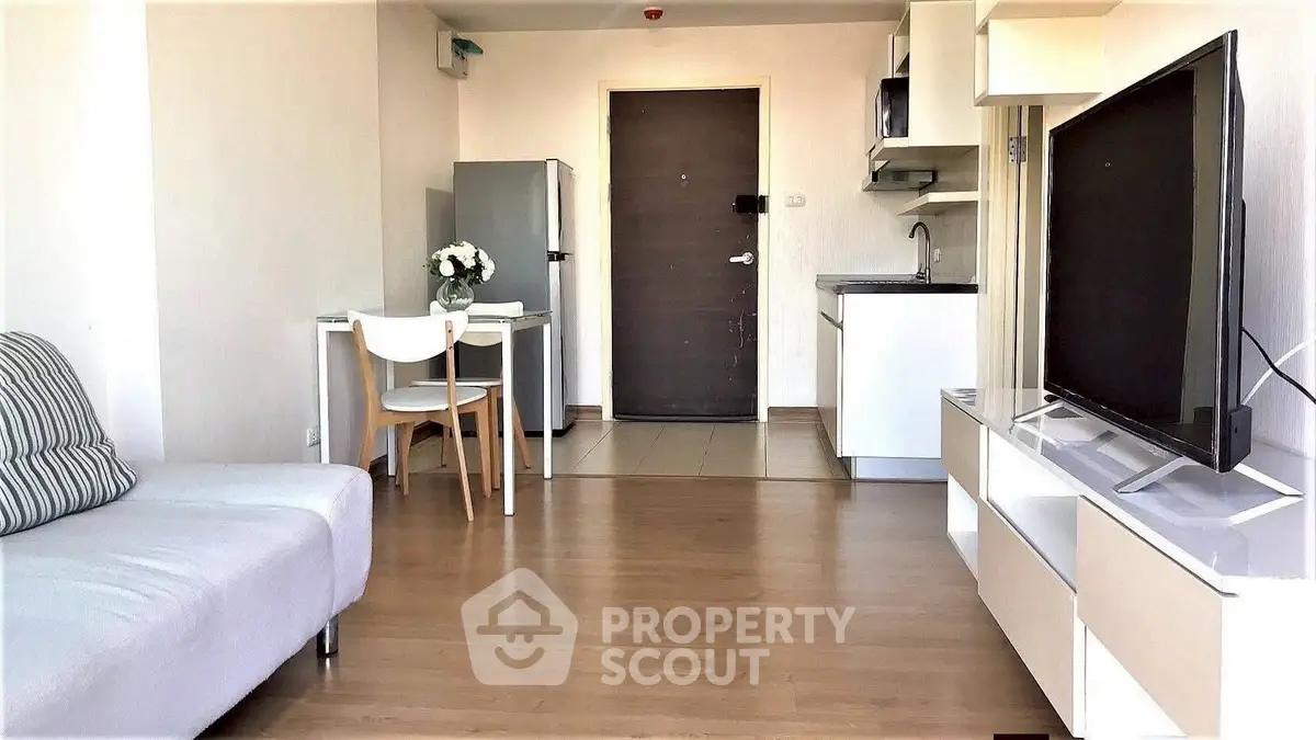 Modern living room with open kitchen, featuring sleek furniture and a flat-screen TV, perfect for urban living.