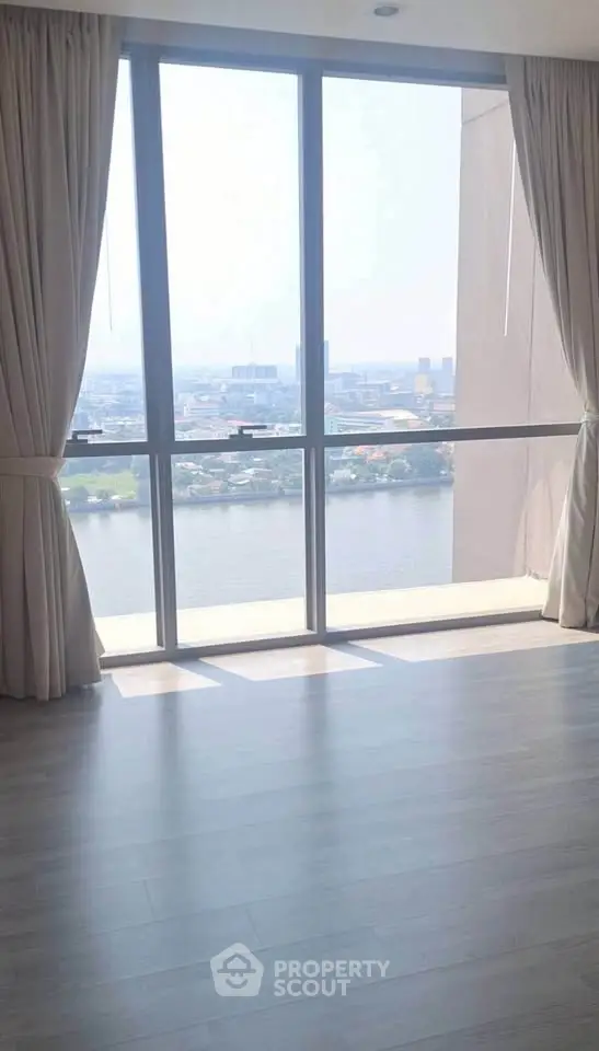 Spacious living room with floor-to-ceiling windows offering stunning river views.