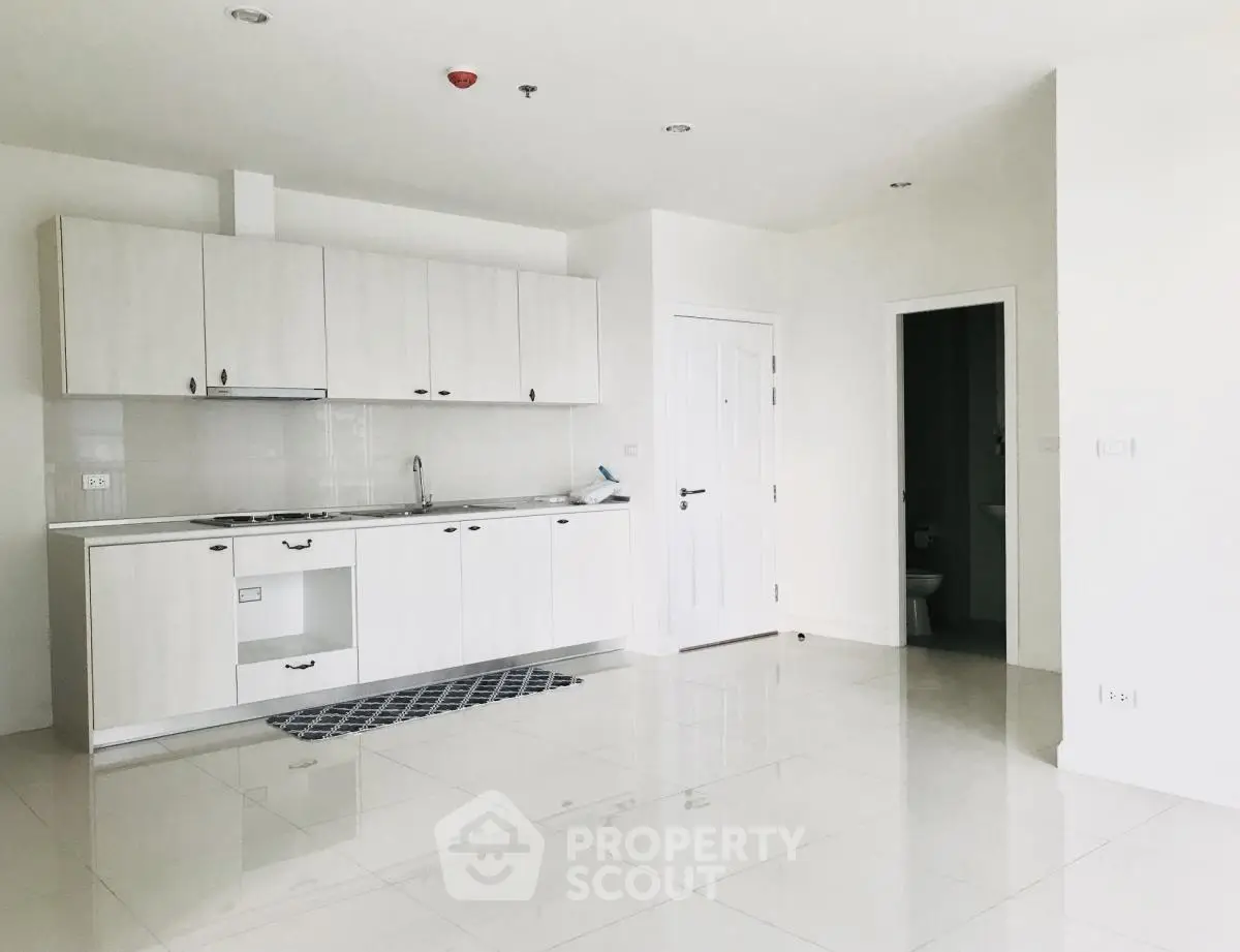 Spacious modern kitchen with sleek white cabinetry and tiled flooring in a bright apartment.