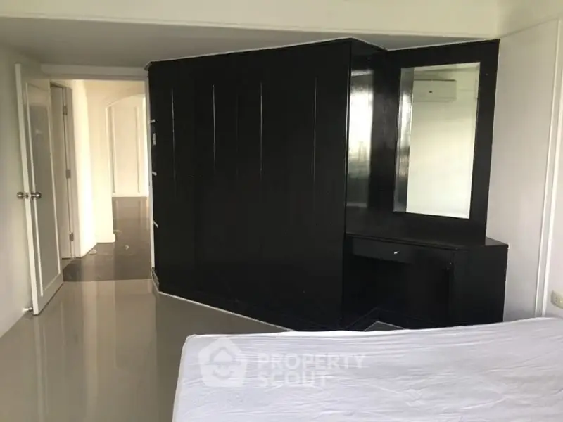 Spacious bedroom with modern black wardrobe and sleek flooring