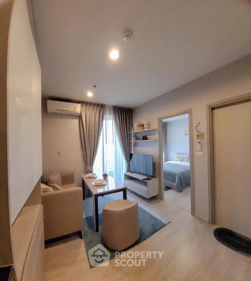 Modern living room with cozy seating and natural light, adjacent to a stylish bedroom.