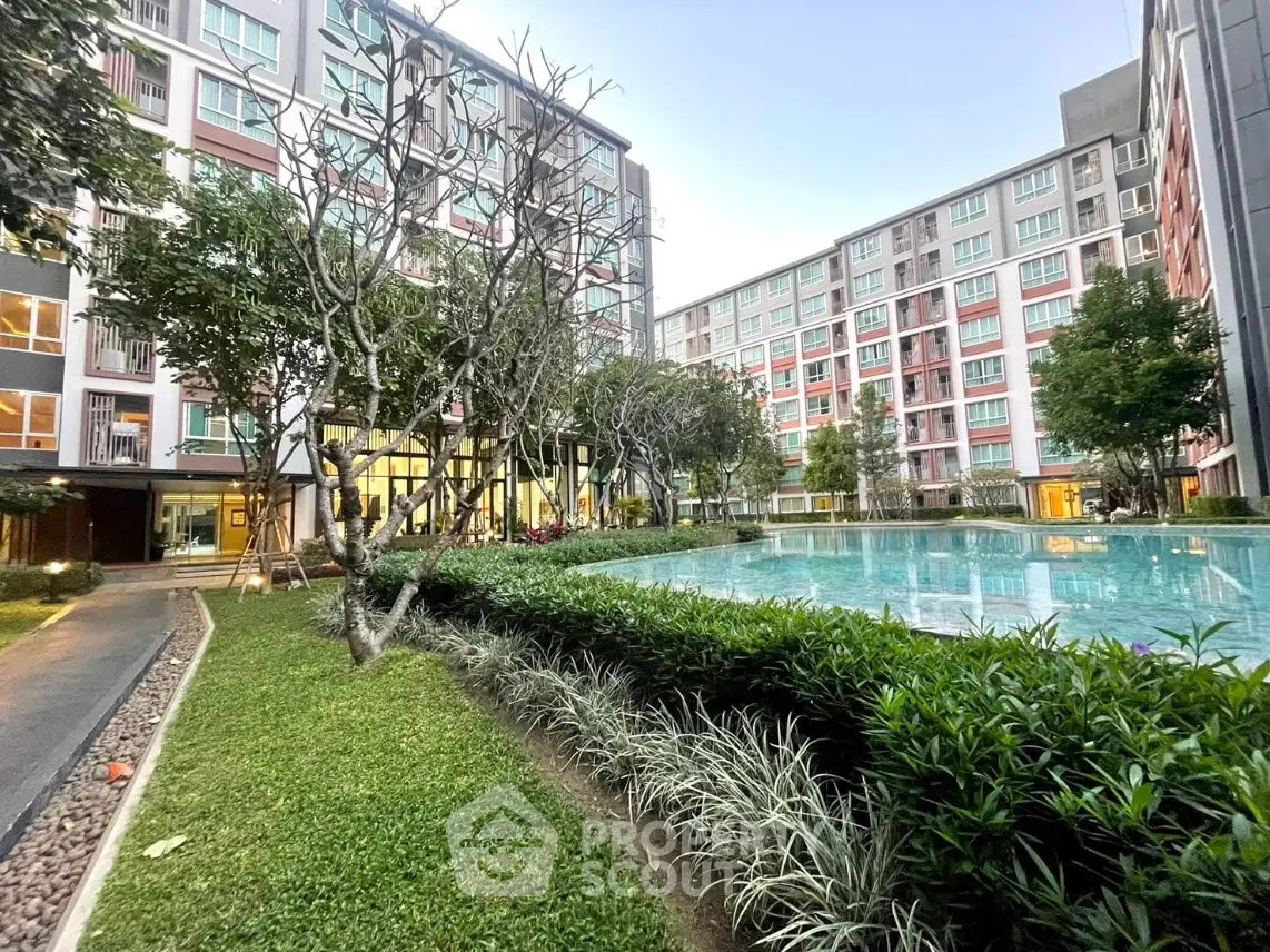 Modern apartment complex with lush garden and inviting pool area.