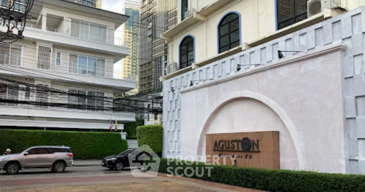 Elegant building entrance with Aguston signage, showcasing modern architecture and urban surroundings.