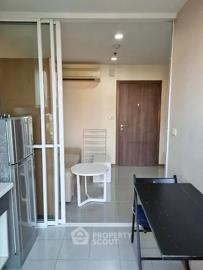 Modern apartment interior with glass partition, compact living area, and sleek furniture.
