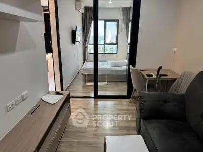 Modern apartment interior with cozy living room and bedroom view, featuring sleek furniture and wooden flooring.