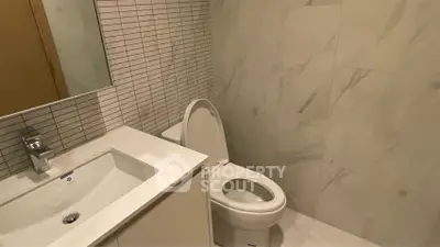 Modern bathroom with sleek white fixtures and marble tile walls