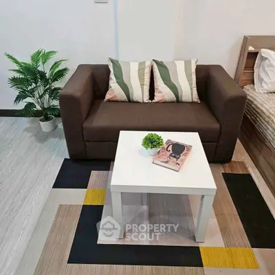 Cozy living room with modern sofa and stylish decor in a compact apartment setting.