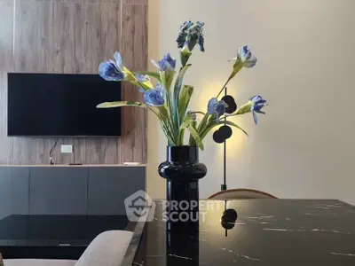 Modern living room with elegant decor and stylish furniture, featuring a sleek black marble table and vibrant floral arrangement.