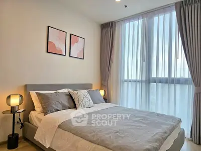 Modern bedroom with stylish decor and large window offering natural light