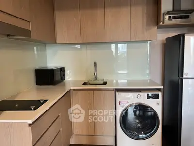 Modern kitchen with sleek cabinetry, washing machine, and glass backsplash
